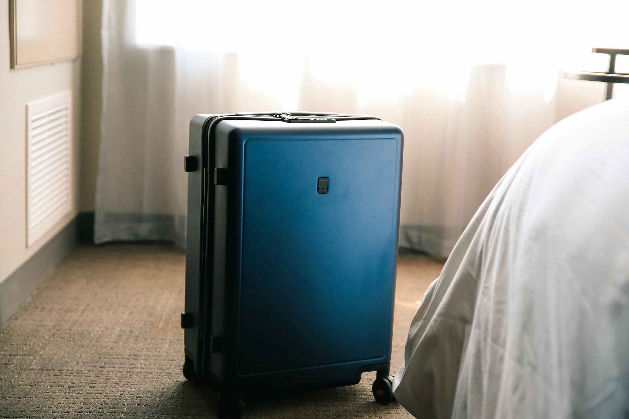 Carry-on suitcase in a hotel room, soft window light